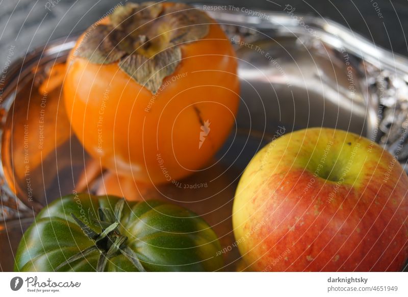Still life of fruit and vegetables in the form of a persimmon or a khaki, an apple and a green tomato on a silver tray Vegetable Nutrition Loneliness