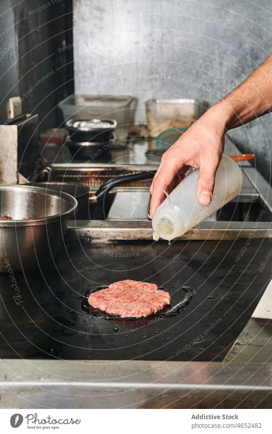 Crop cook pouring oil while frying burger cutlet chef patty fast food sauce junk food stove kitchen bottle food truck work prepare beef ingredient culinary job
