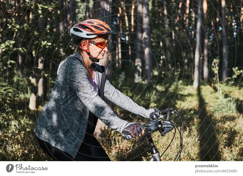 Active woman cycling on forest road. Female riding bicycle off-road route on summer vacation day trip adventure biking recreation travel bike action activity