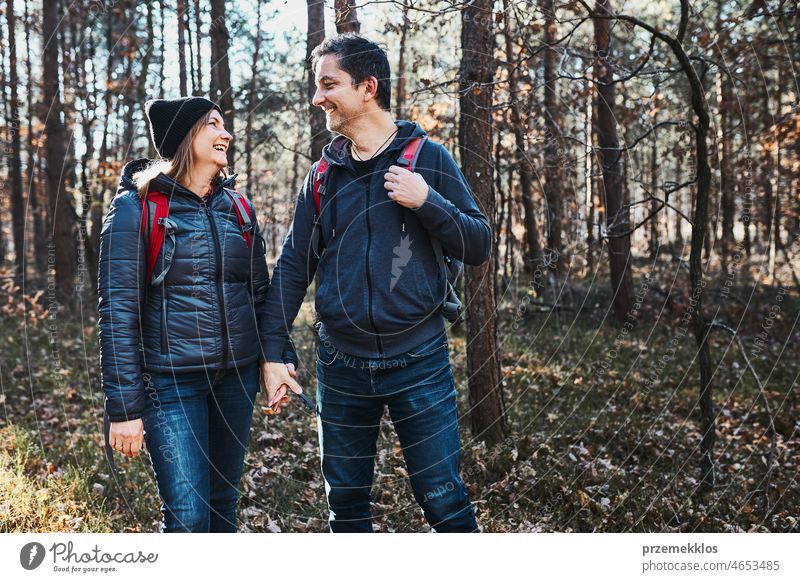Couple holding hands enjoying trip while vacation day. Hikers with backpacks walking on forest path on sunny day hiking adventure travel gesture exploring