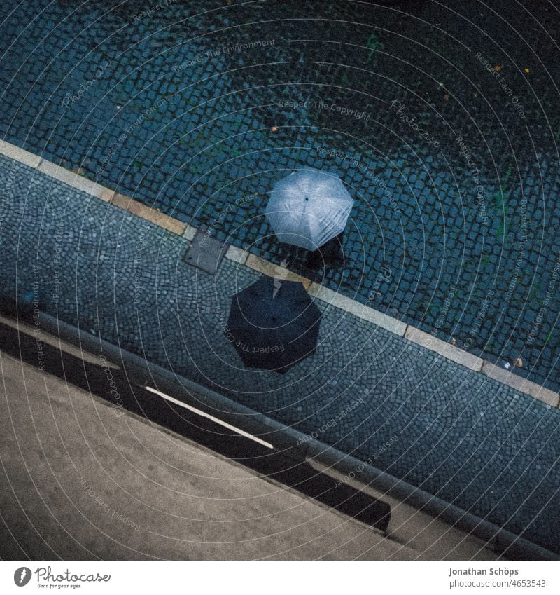 Bird's eye view of two people with umbrella on street in rain Bird's-eye view Umbrella Rain Wet Street Paving stone paved Footpath Bad weather Weather