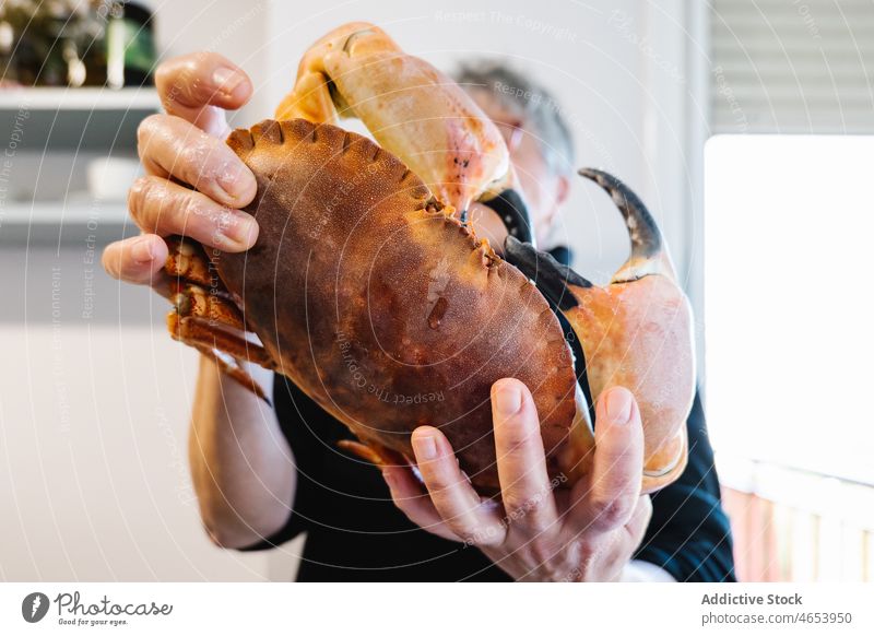 Woman showing raw crab in kitchen woman seafood uncooked cuisine delicacy delicatessen home light fresh claw demonstrate appetizing palatable domestic female
