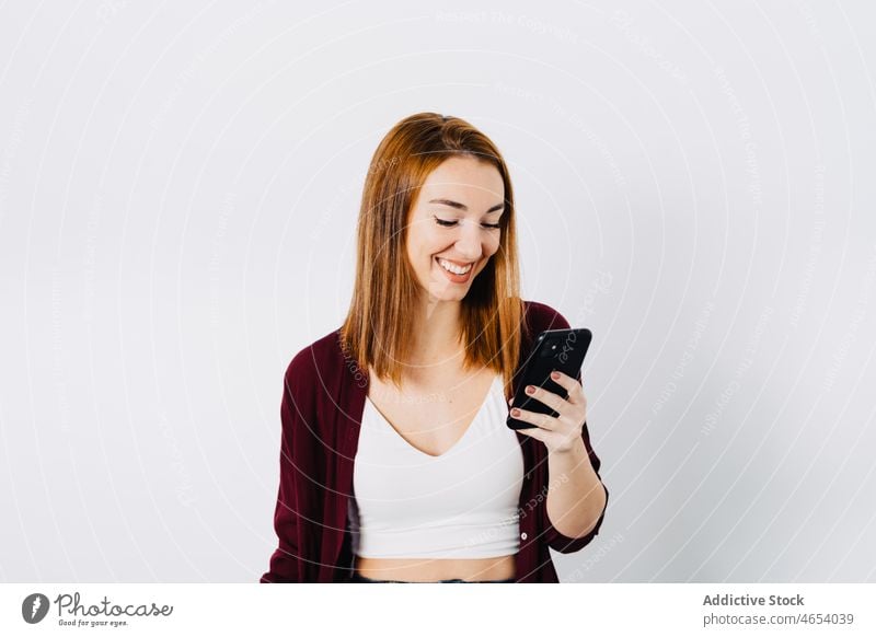 Smiling redhead woman using cellphone smartphone browsing online internet connection social media female ginger cheerful happy surfing mobile smile positive