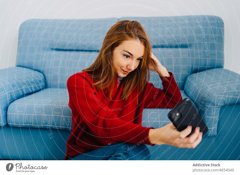 Woman on sofa taking selfie on smartphone woman self portrait using couch lounge chill comfort rest redhead take photo memory shoot device female sit red hair