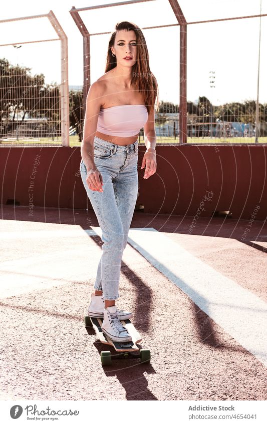 Young woman riding longboard in park skater skate park hobby activity city urban street summer female ride slim focus energy millennial young cool long hair