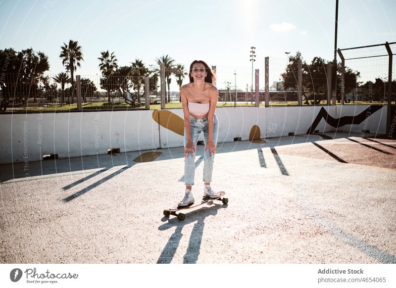 Young smiling woman riding longboard in park skater skate park hobby activity smile city urban street summer female ride happy slim focus energy millennial
