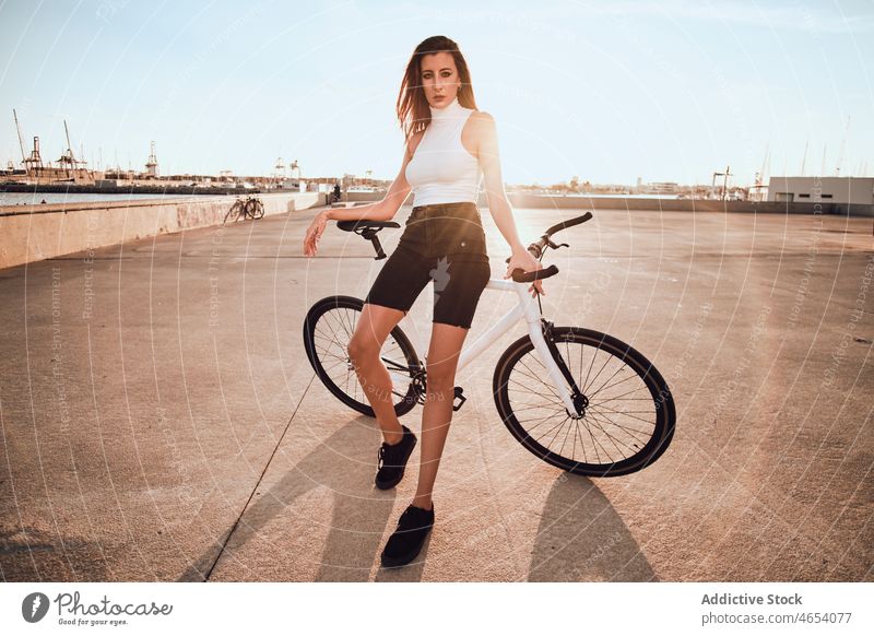Woman riding bicycle on pavement woman park activity summer weekend hobby female ride leisure carefree young blue sky enjoy street free time relax lady urban