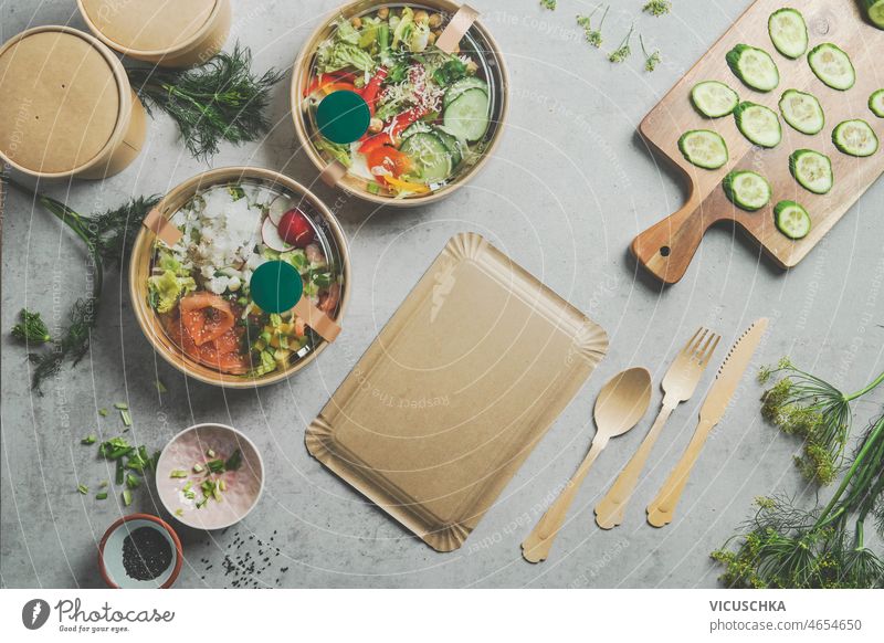 Healthy salad lunch in take away food bowls with sustainable containers healthy salad grey kitchen table wooden cutlery cutting board vegetables eco-friendly