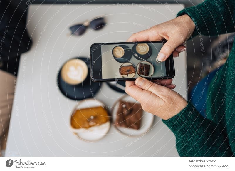 Woman filming dessert with latte on smartphone woman blogger using cake record video meeting social media female latte art gadget device friend together coffee