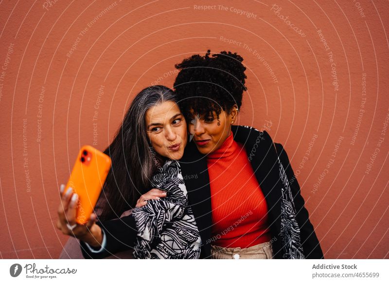 Happy multiracial women taking self portrait on mobile phone friend selfie smartphone cellphone smile together having fun using female best friend spend time