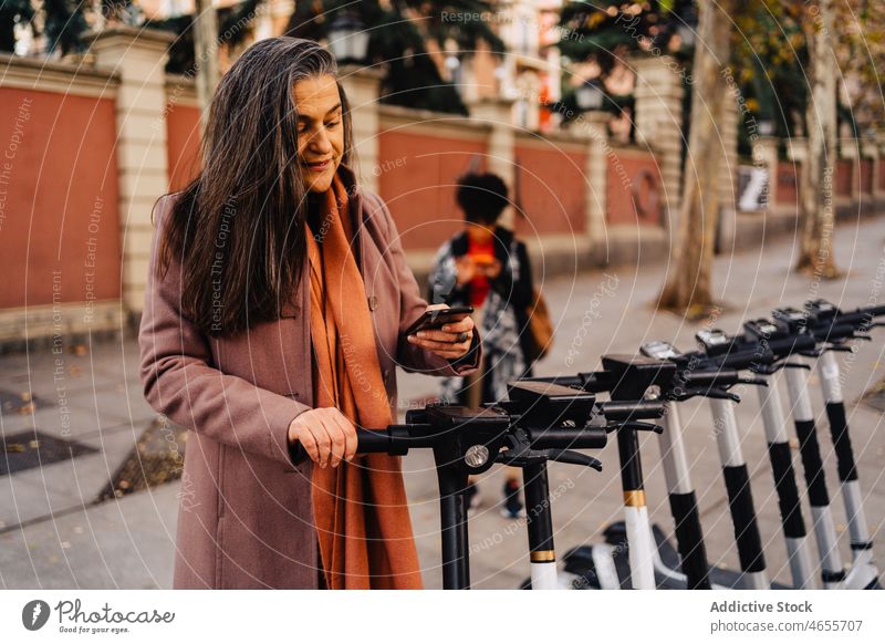 Ethnic female paying for electric scooter on street woman smartphone cellphone rent purchase payment contactless application city transaction transfer client
