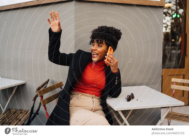 Cheerful black woman talking on smartphone and waving hand excited using phone call greeting happy hello wave hand cool female glad gesture expressive hi