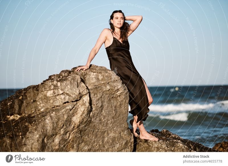 Stylish young female leaning on stone on seashore woman rock dress sensual summer rocky vacation coast water wet recreation formation seaside nature gorgeous