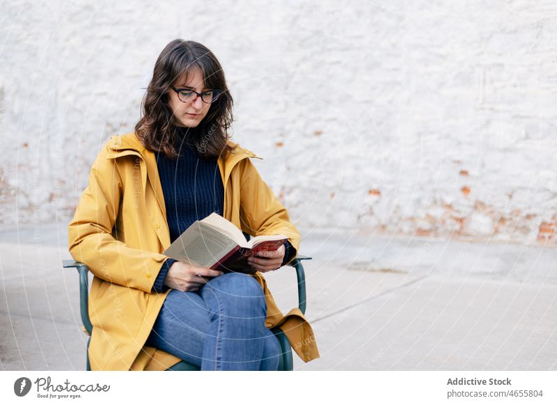 Woman reading book on street woman hobby bookworm literature interest novel building wall white style urban appearance city female bright town lady outerwear