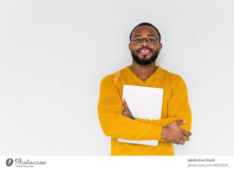 Smiling black man with laptop netbook freelance individuality device using worker employee online male african american smile positive teeth gap eyeglasses