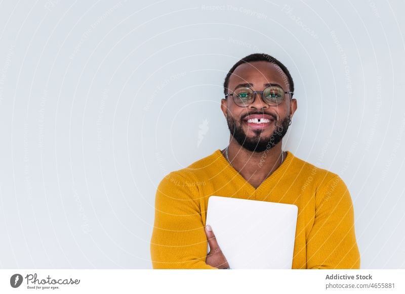 Smiling black man with laptop netbook freelance individuality device using worker employee online male african american smile positive teeth gap eyeglasses
