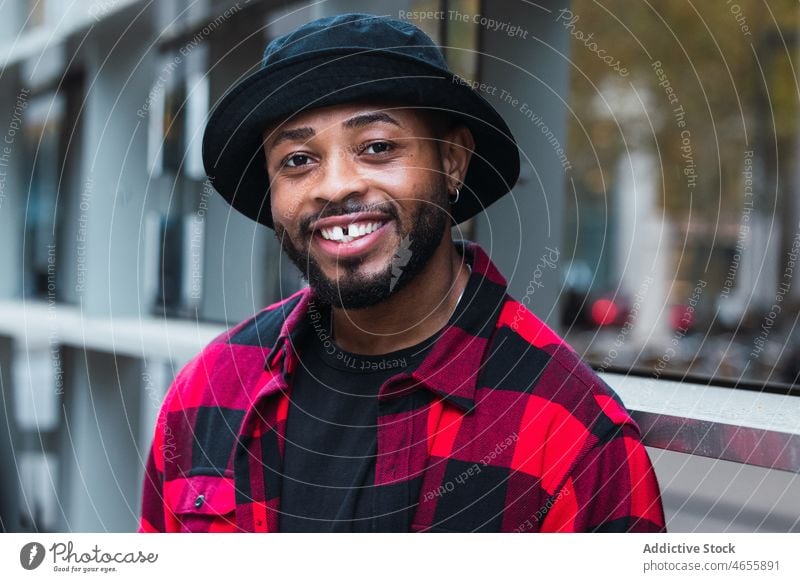 Cheerful black man in stylish outfit on street style city appearance individuality personality checkered shirt hat male african american urban positive beard
