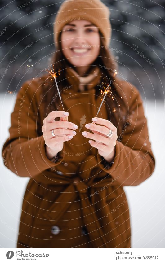 Woman standing at snowy park and holding sparklers woman new year christmas weather celebration tradition outdoors festive mood event fireworks one person