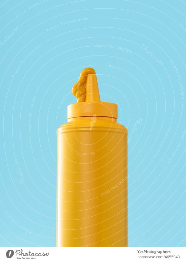 Mustard plastic bottle isolated on a blue background. bbq blank clean close-up color condiment container copy space cream creative cut out delicious design