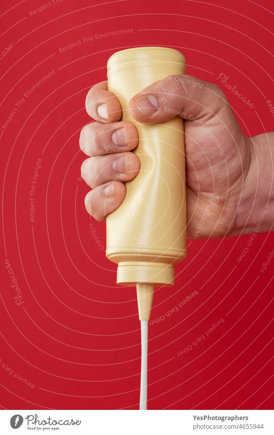 Squeezing a mayonnaise bottle isolated on a red background. bbq clean close-up color container cream creative cut out delicious design dressing drip fast food