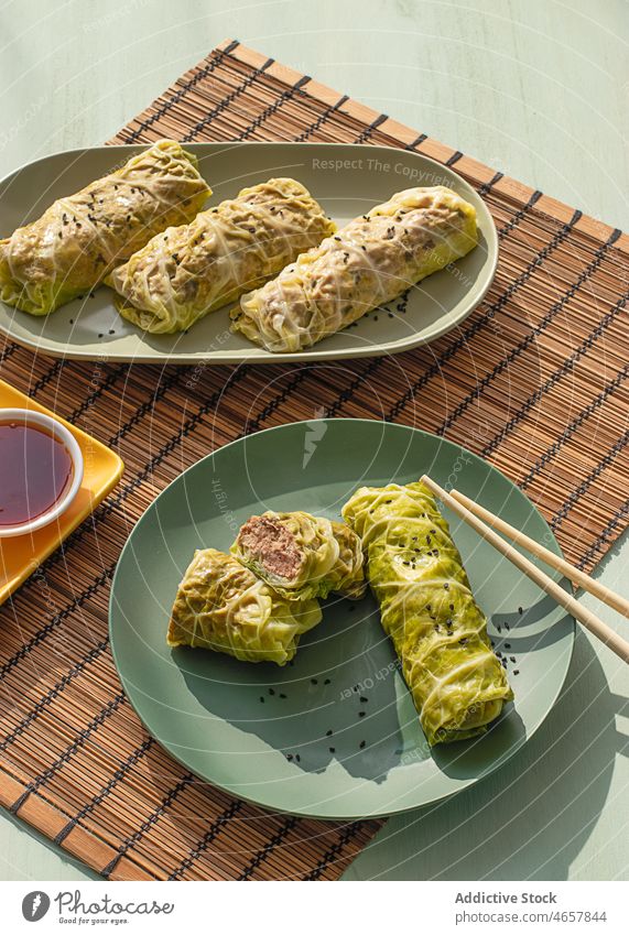 Cabbage spring rolls near chopsticks cabbage chinese asiatic oriental asian cooking leaf table filling filled savory place mat souce bamboo sweet chilly