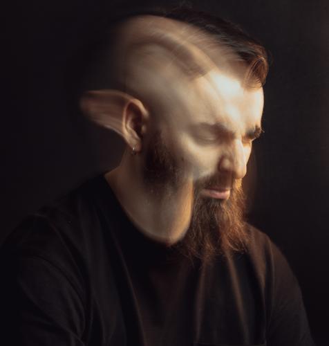 Double exposure artistic portrait of a handsome hipster male worried and angry about something with cinematic light. Dark background with dark tones. Artistic mental health concept. Demons inside.