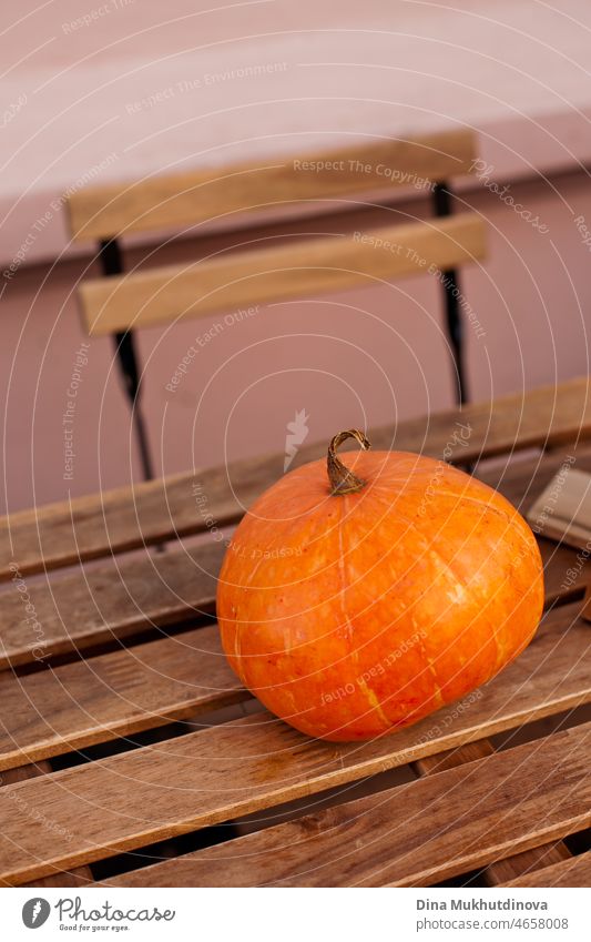 A ripe orange pumpkin on a wooden table at the terrace at home or restaurant patio. Small size pumpkin on old wooden table. squash gourd thanksgiving halloween