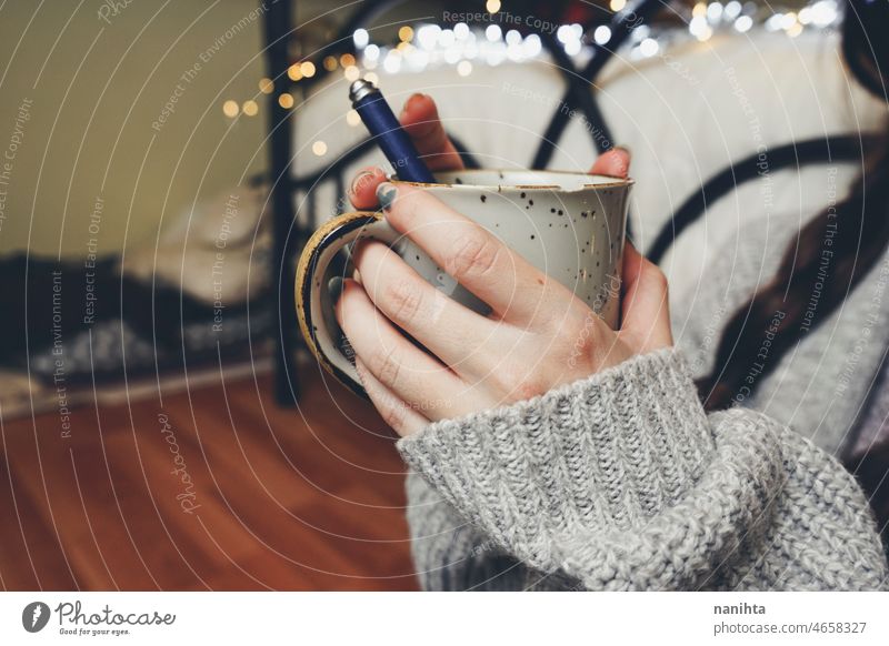 Woman hands holding a warm cup of coffee tea autumn tones light bokeh wool woolen sweater home woman young youth black warmth delicate fragile scene mood moody