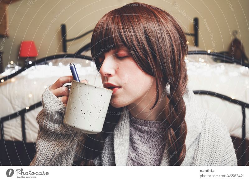 Young and dreamy woman enjoying a cup of coffee home warm tea winter autumn mood moody portrait comfort quiet tranquility life lifestyle comfy cute brunette