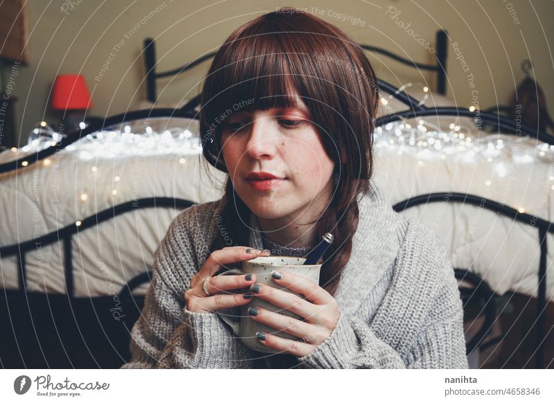 Young and dreamy woman enjoying a cup of coffee home warm tea winter autumn mood moody portrait comfort quiet tranquility life lifestyle comfy cute brunette