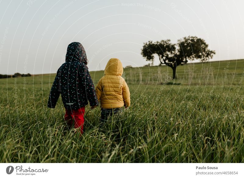 Brother and sister walking on grass Child childhood two people Brothers and sisters Together togetherness Nature explore Colour photo Caucasian Happiness