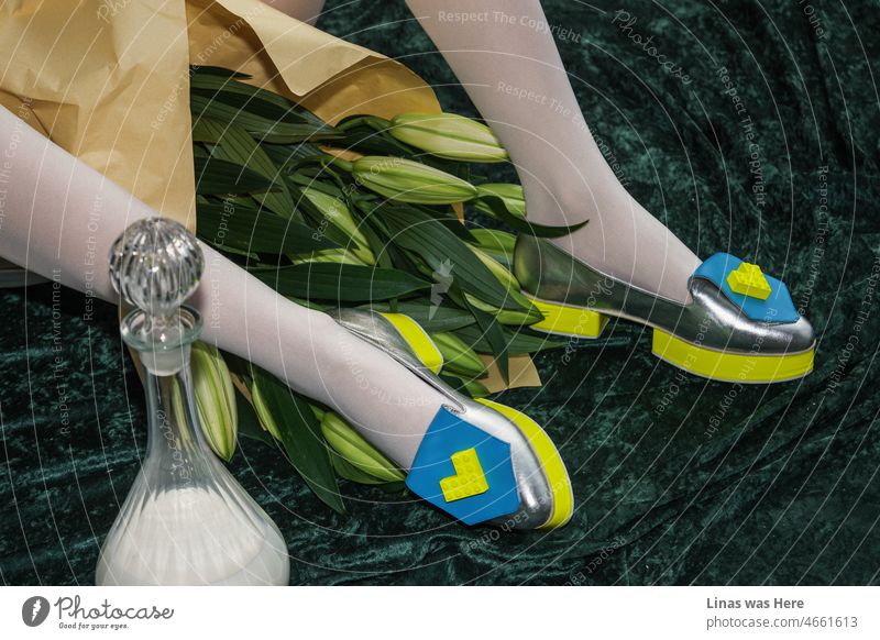 A bouquet given to this avant-garde shoe model is not the main subject in the image. On the other hand, silver shoes are definitely something extraordinary. With some lego details, electric yellow details, and a fashionista look in general.