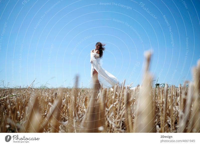 A lonely Woman With Long Wavy Hair, Dressed In A White Dress, Enjoys A Wheat Field At Sunset. woman female countryside summer lifestyle beauty freedom girl