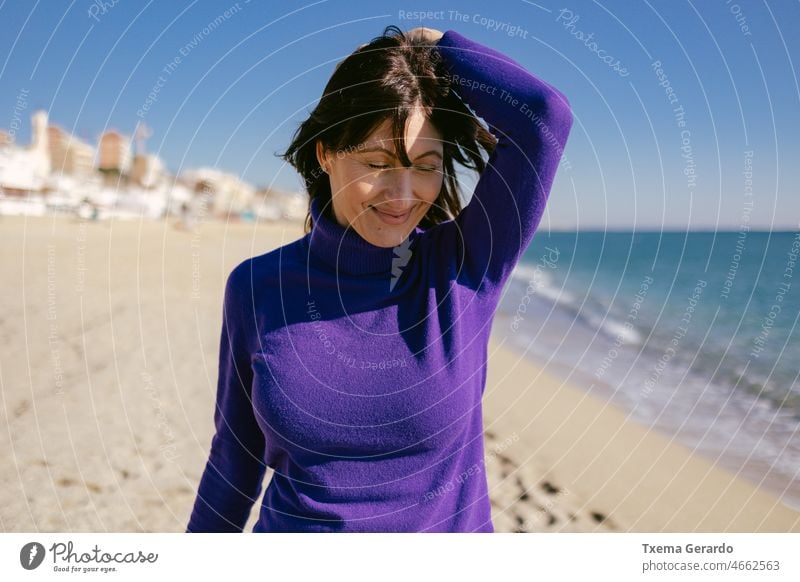 Beautiful happy mature woman enjoying a sunny winter day at the beach 45-50 years sea mindfulness freedom emotion positive relaxation standing tranquility