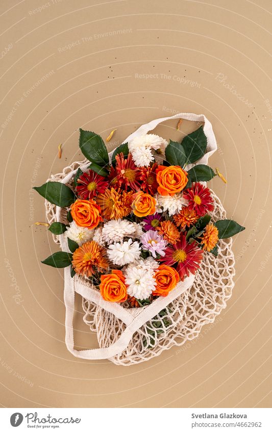 Orange and red garden flowers in the mesh bag Mockup for card Background in natural earth tones Roses, daisies, chrysanthemums minimal mockup wedding background
