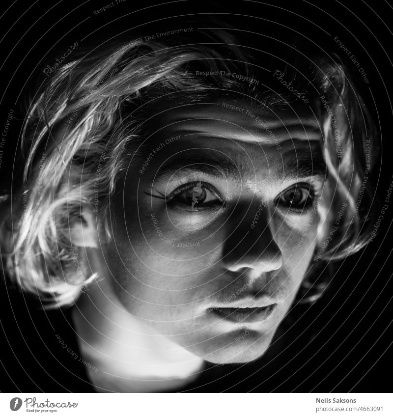 portrait of young teenager boy eyes light illuminated caucasian blonde hair look looking big eyes darkness pretty hairstyle elegant shadows sparkle sparkling