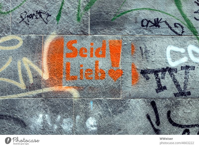 On a scrawled wall, in orange paint, is the exhortation "Be Kind!" Wall (building) Wall (barrier) Graffiti writing Sign Characters words Orange Red Colour