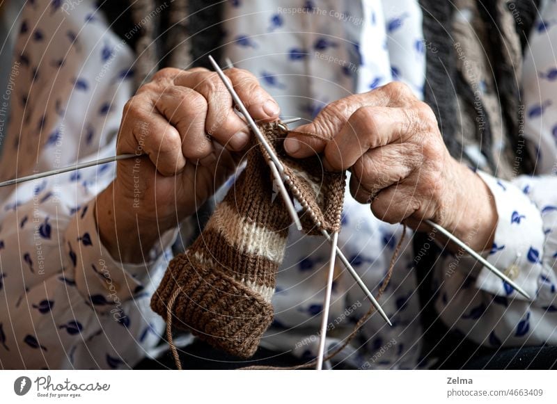 Close up of the hands of an elderly woman knitting sock old grandma craft age life senior closeup osteoarthritis disease fingers j oint pain bone deformation
