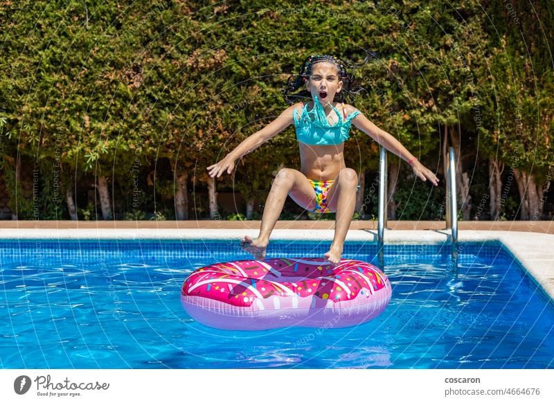 Lttle girl jumping on a rubber ring into a pool activity beautiful bikini buoy child childhood children dive donut doughnut float fun funny happy inflatable kid
