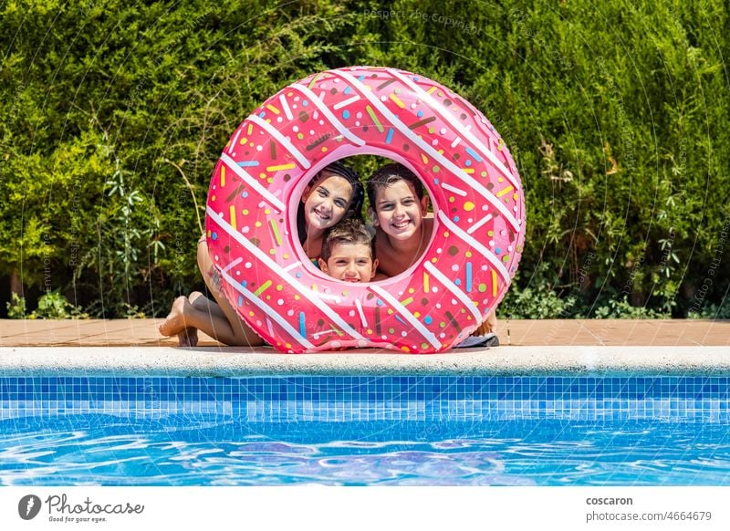 Three kids posing on a hole of a rubber ring activity beautiful boy boys caucasian child childhood children cute donut edge enjoy floating friends fun girl
