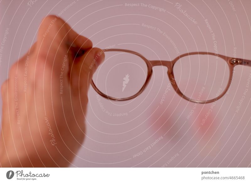One hand holds a pair of glasses in pink. See through, see through. Visual aid Eyeglasses visual aid Vista review Looking Vision Person wearing glasses