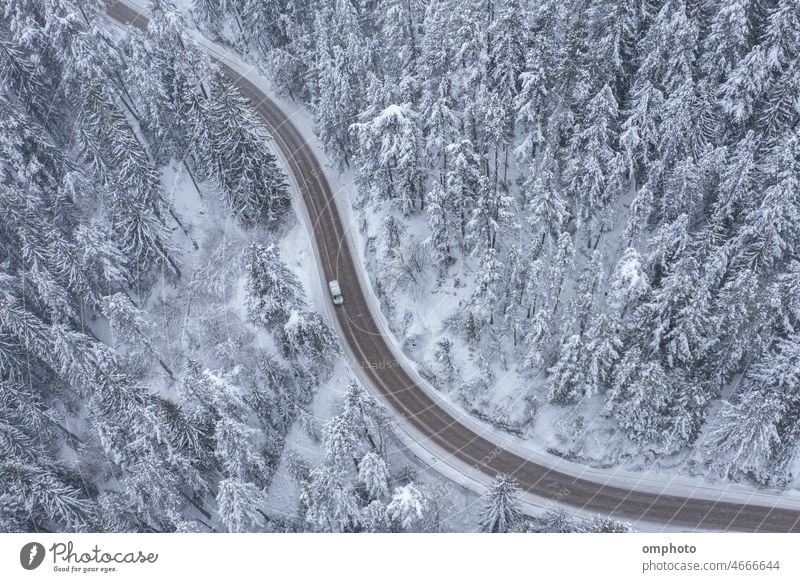 Snowy Winding Curving Mountain Road with Moving Car During Snowfall landscape aerial winter forest snow snowfall pines road curving winding car truck meandering