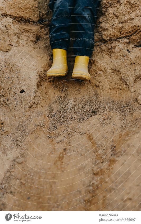 Child with Yellow rubber boots on sand Close-up Rubber boots Sand Dirty Footwear Legs Colour photo Boots Exterior shot Feet Bad weather Playing Infancy