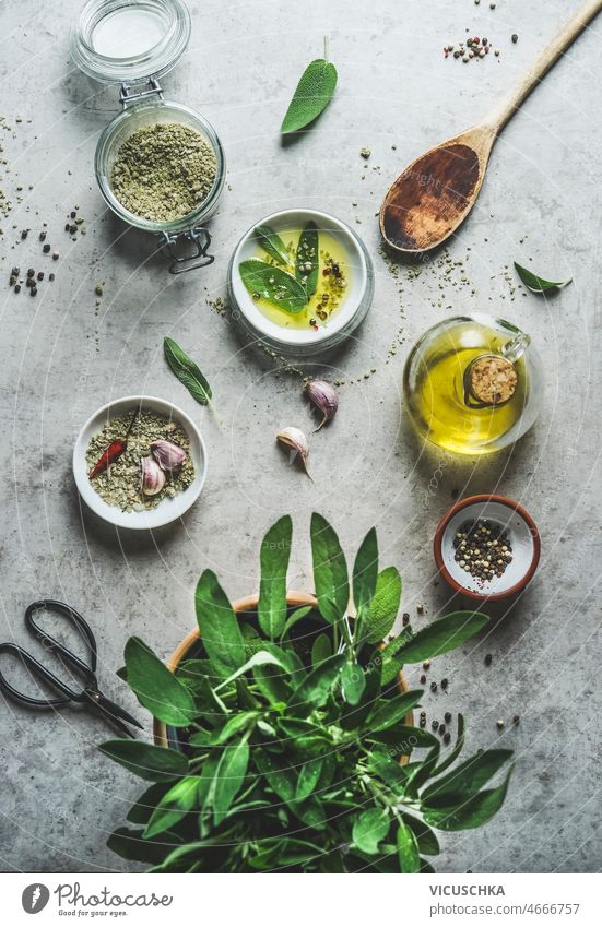 Healthy cooking ingredients: herbal salt, olive oil,sage,pepper, garlic,chili and kitchen utensils healthy grey concrete table preparation delicious herbs
