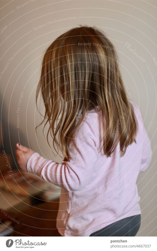 Back view of small child with long hair standing in space and moving his arms Child Stand move Arm Gymnastics kids yoga long hairs Room books Concentrate Girl
