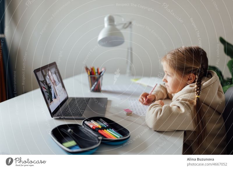 Caucasian kid studying online at home and using laptop. Distance or remote learning for child. Pretty stylish schoolgirl studying homework math during coronavirus covid-19 quarantine and social distancing