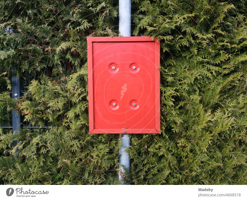 Empty red plastic board in front of green hedge at an abandoned bus stop in Oerlinghausen near Bielefeld on Hermannsweg in the Teutoburg Forest in East Westphalia-Lippe, Germany