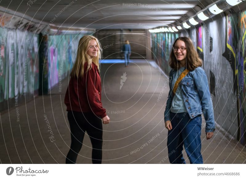 Two girls walk through pedestrian tunnel and look around laughing for a moment Tunnel Girl Laughter cheerful two in twos girlfriends fun Joy unetrwegs stroll