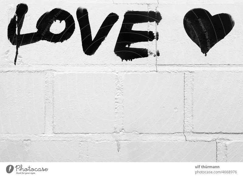 The word love painted in black letters on a white brick wall heart black and white symbol emotions characters graffiti romance bricks