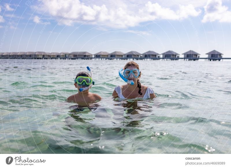 Mother and son snorkeling on the Maldive Islands beach bikini boy bungalows child coral family fins girl holiday honeymoon hotel influencer island kid leisure